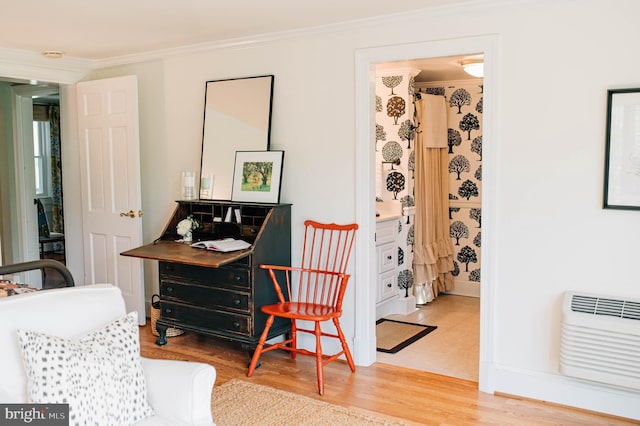 sitting room with a wall unit AC, hardwood / wood-style floors, and crown molding