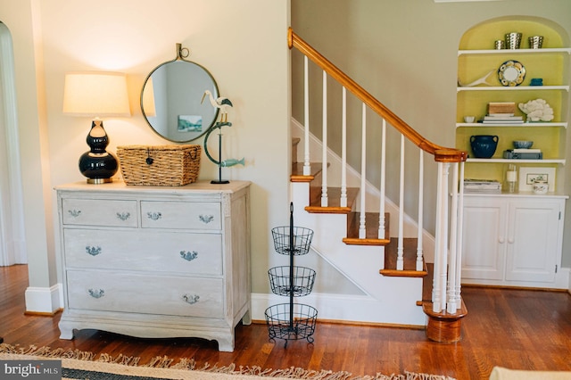 stairway with hardwood / wood-style flooring and built in shelves