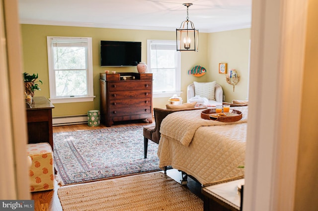 bedroom featuring ornamental molding, an inviting chandelier, a baseboard radiator, and wood-type flooring