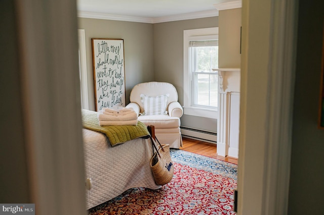 bedroom with hardwood / wood-style floors, crown molding, and a baseboard heating unit