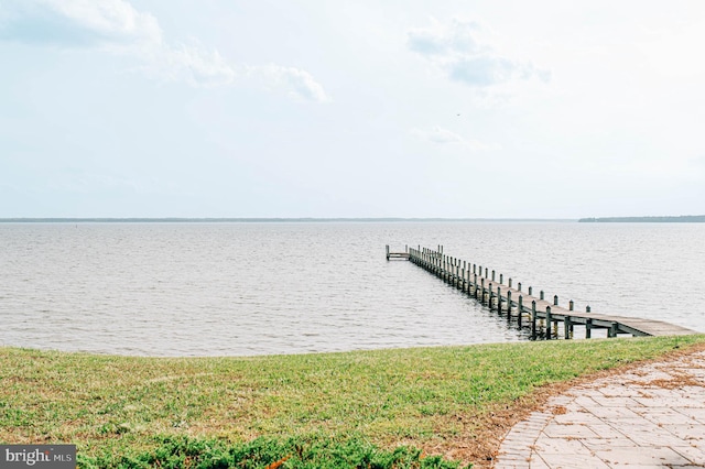 view of dock featuring a lawn and a water view