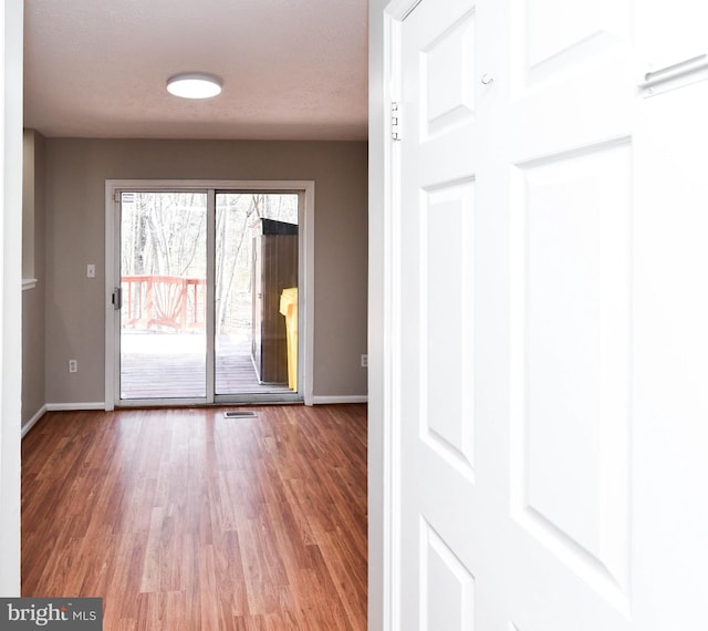 unfurnished room featuring wood finished floors, visible vents, and baseboards