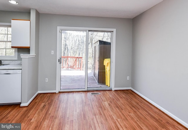 doorway to outside with light wood finished floors, visible vents, and baseboards