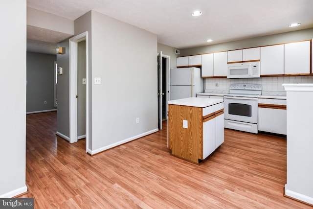 kitchen with a center island, light countertops, white appliances, and white cabinets