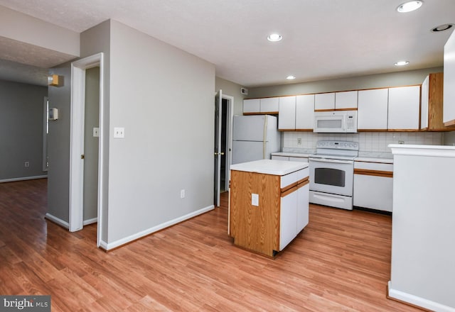 kitchen featuring white appliances, a kitchen island, white cabinetry, light countertops, and decorative backsplash