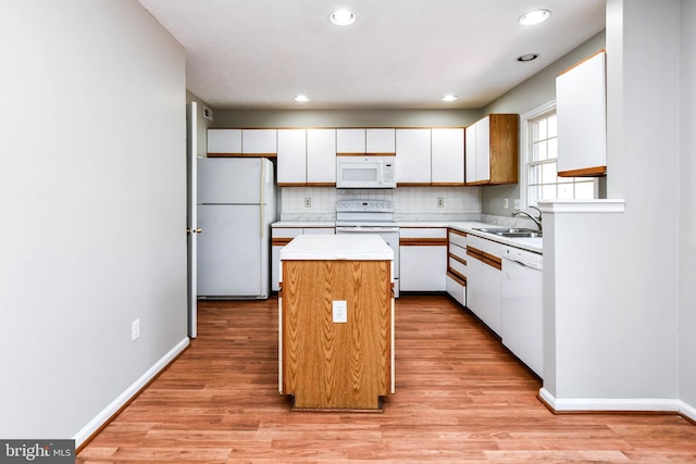 kitchen with light countertops, white appliances, white cabinetry, and a kitchen island