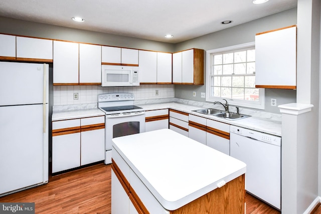 kitchen featuring white appliances, light countertops, a sink, and white cabinets