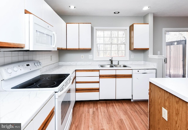 kitchen with white appliances, a sink, white cabinets, light countertops, and light wood-type flooring