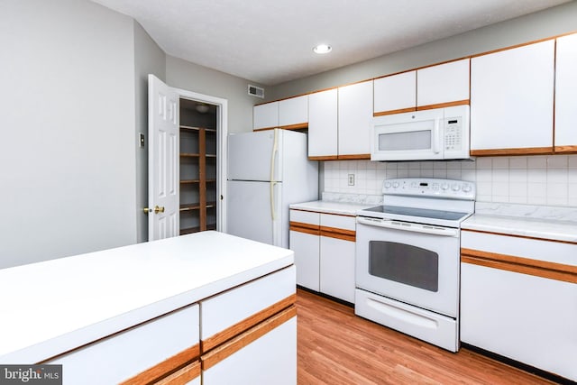 kitchen with white appliances, white cabinetry, light countertops, and decorative backsplash