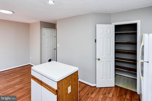 interior space with light wood finished floors, baseboards, light countertops, and freestanding refrigerator