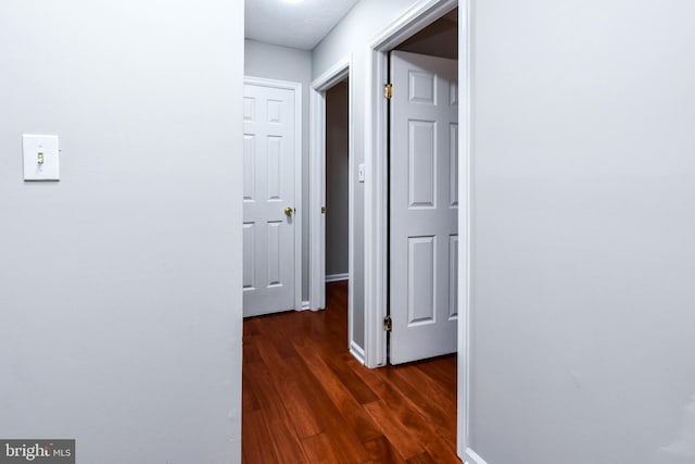 hall with baseboards and dark wood finished floors