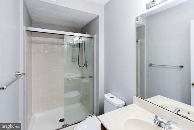 full bath featuring a stall shower, a textured ceiling, toilet, and vanity