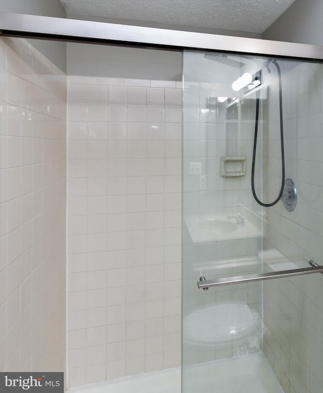 full bathroom with a textured ceiling and a stall shower