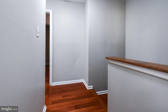 corridor featuring dark wood-type flooring and baseboards