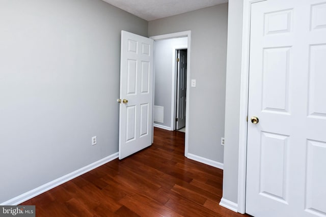 unfurnished bedroom with dark wood-style floors and baseboards