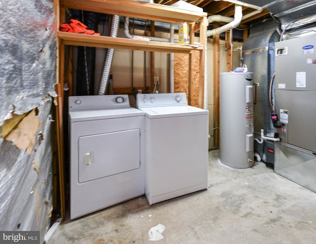 laundry room with heating unit, laundry area, washing machine and dryer, and electric water heater