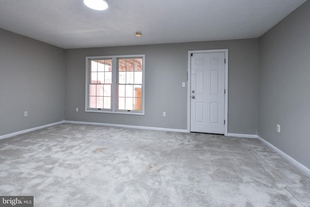 unfurnished room with light carpet and baseboards