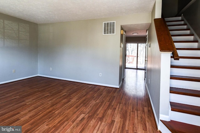 unfurnished room featuring baseboards, stairs, visible vents, and dark wood-style flooring