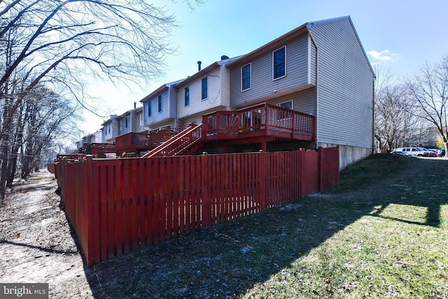 rear view of house featuring stairway, a deck, and a lawn