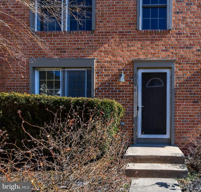 doorway to property featuring brick siding