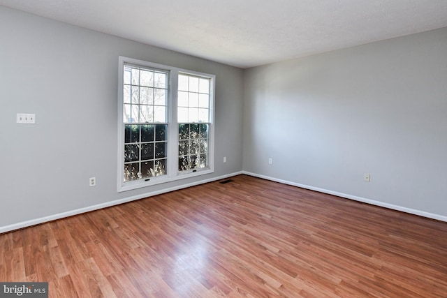 spare room with baseboards and wood finished floors