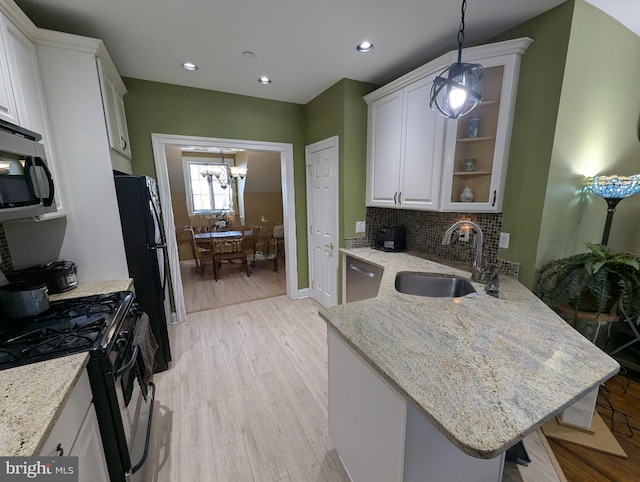 kitchen with sink, white cabinetry, pendant lighting, black fridge, and gas range oven