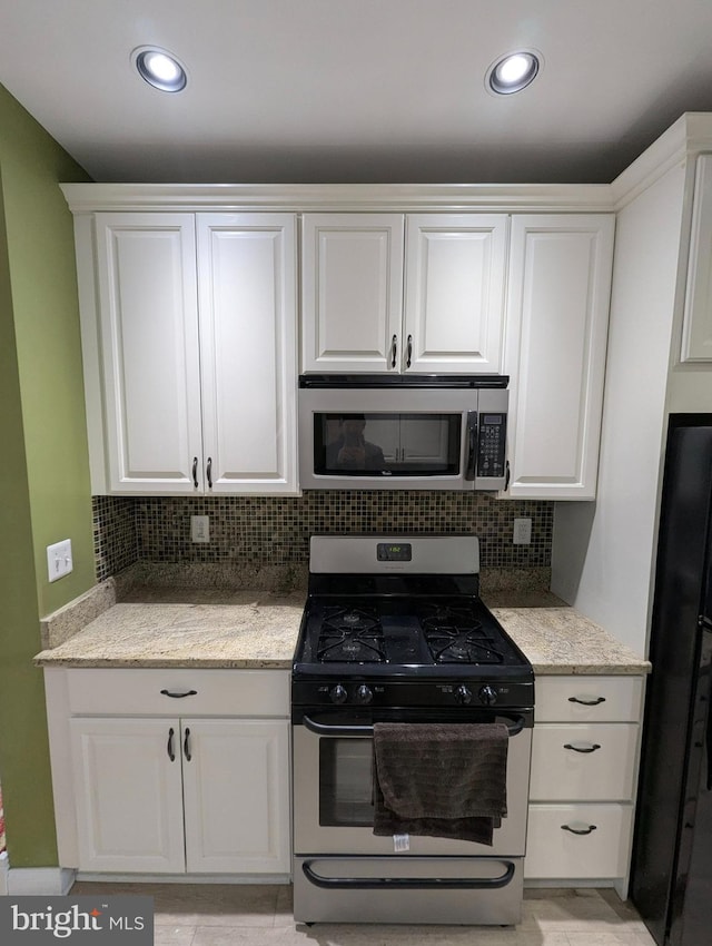 kitchen featuring white cabinetry, backsplash, stainless steel appliances, and light stone counters