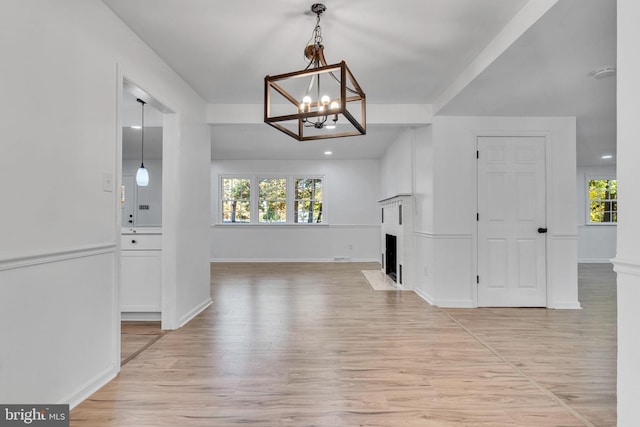 unfurnished living room with a notable chandelier and light hardwood / wood-style flooring