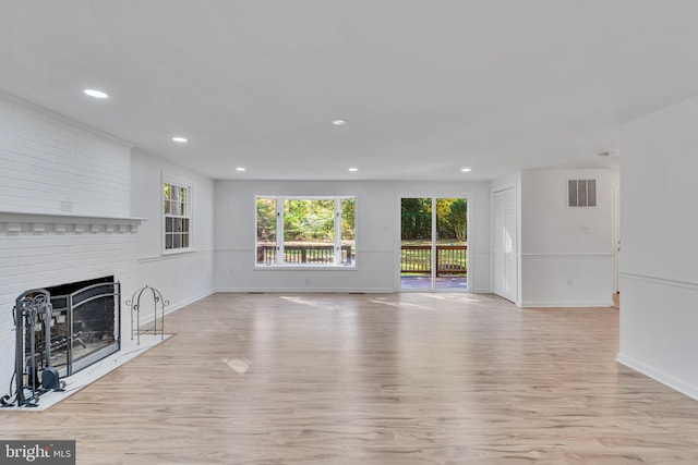 unfurnished living room featuring a brick fireplace and light wood-type flooring