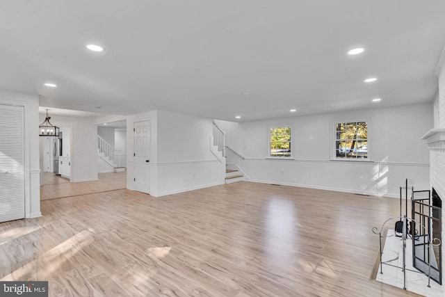 living room with a brick fireplace and light hardwood / wood-style floors