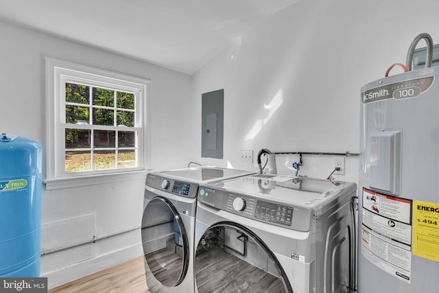 clothes washing area featuring water heater, washing machine and clothes dryer, electric panel, and light hardwood / wood-style flooring