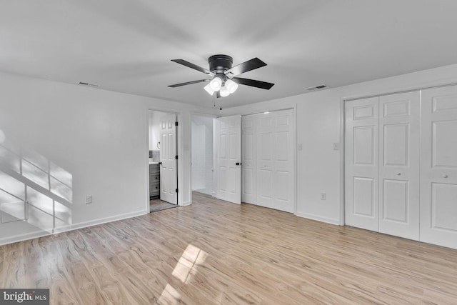 unfurnished bedroom with ceiling fan, light hardwood / wood-style flooring, connected bathroom, and two closets