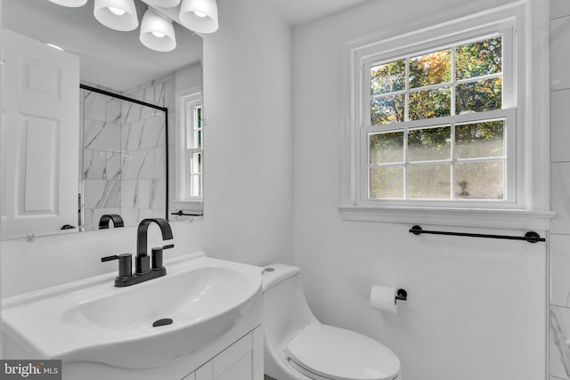 bathroom featuring toilet, a shower, and vanity