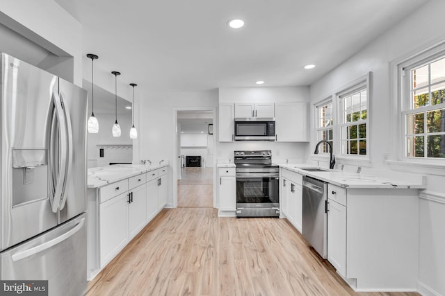 kitchen featuring light stone counters, stainless steel appliances, pendant lighting, and white cabinetry