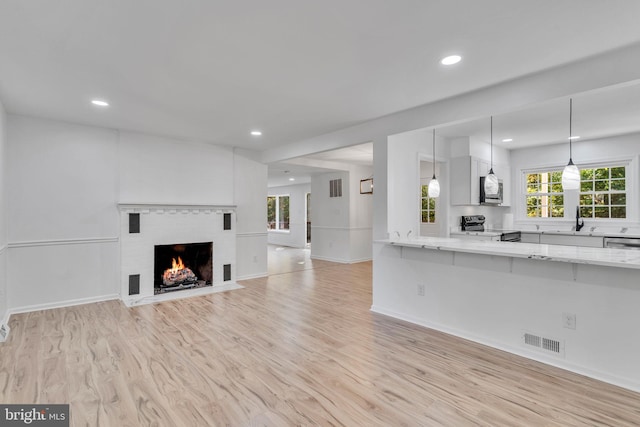 unfurnished living room featuring a fireplace, light hardwood / wood-style flooring, and sink