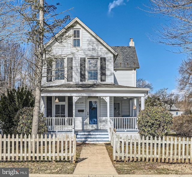 view of front of house with a fenced front yard, a chimney, and a porch