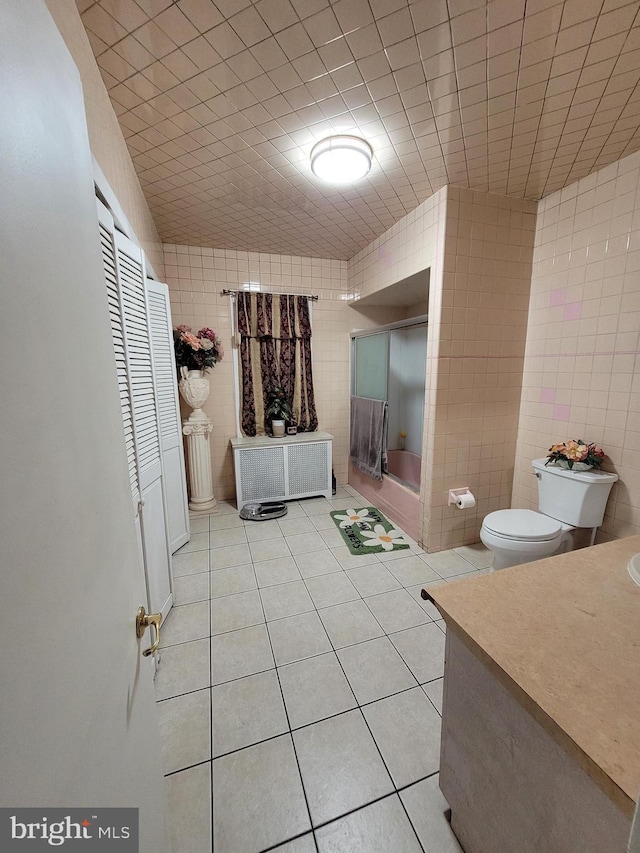 full bathroom with toilet, tile patterned flooring, tile walls, and radiator heating unit