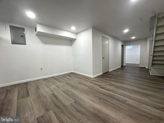 basement featuring electric panel and dark hardwood / wood-style flooring