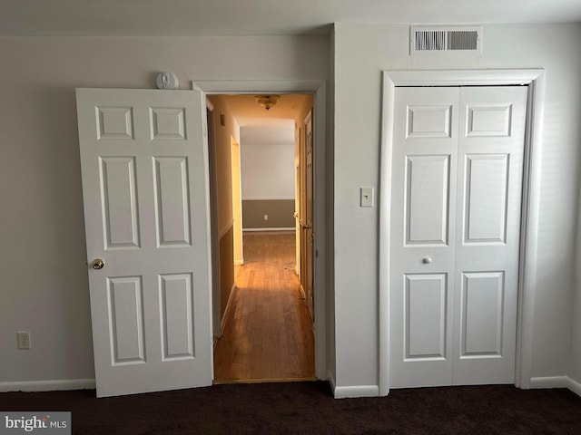 hallway featuring dark colored carpet