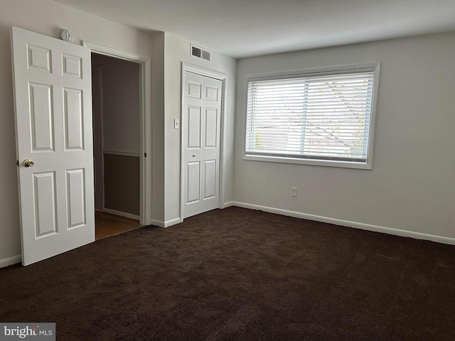 unfurnished bedroom featuring a closet and dark colored carpet