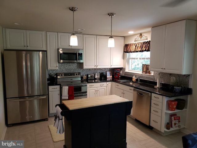 kitchen featuring appliances with stainless steel finishes, a center island, decorative light fixtures, white cabinets, and sink