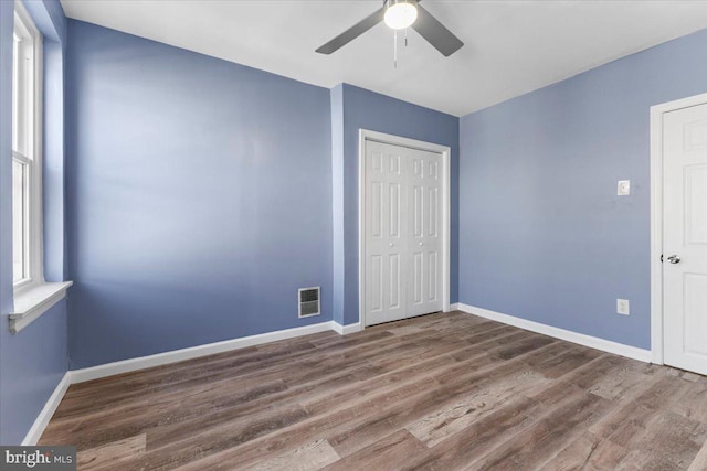 unfurnished bedroom with wood-type flooring, ceiling fan, and a closet