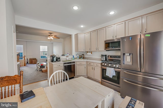 kitchen with appliances with stainless steel finishes, ceiling fan, light carpet, and cream cabinetry