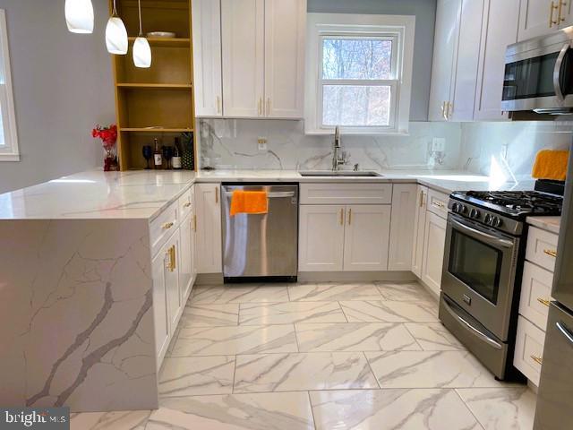 kitchen featuring decorative light fixtures, kitchen peninsula, sink, white cabinetry, and stainless steel appliances