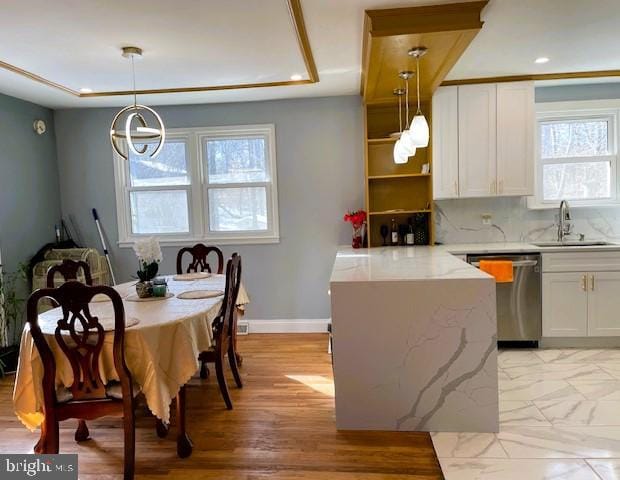 kitchen featuring decorative light fixtures, sink, white cabinets, and dishwasher