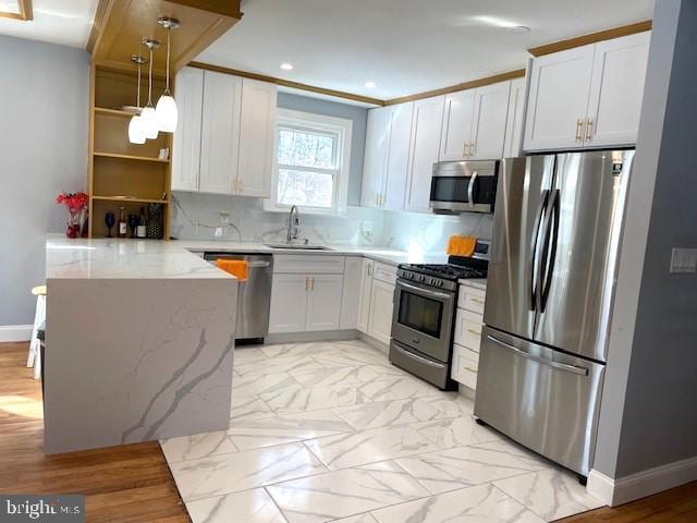 kitchen with decorative light fixtures, kitchen peninsula, sink, appliances with stainless steel finishes, and white cabinets