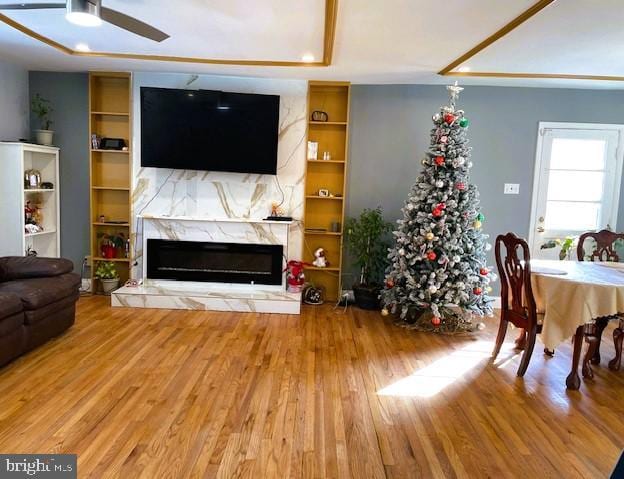 living room featuring ceiling fan, built in shelves, and hardwood / wood-style flooring