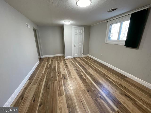 interior space with a textured ceiling and hardwood / wood-style floors