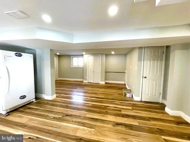 basement featuring wood-type flooring and white refrigerator