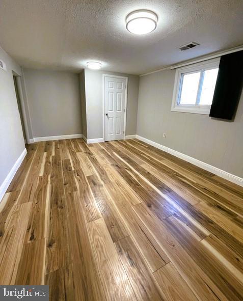 basement featuring hardwood / wood-style floors and a textured ceiling